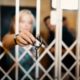 Frau hält Schlüssel durch Gitter von Escape Room Wien – bester Escape Room der Welt