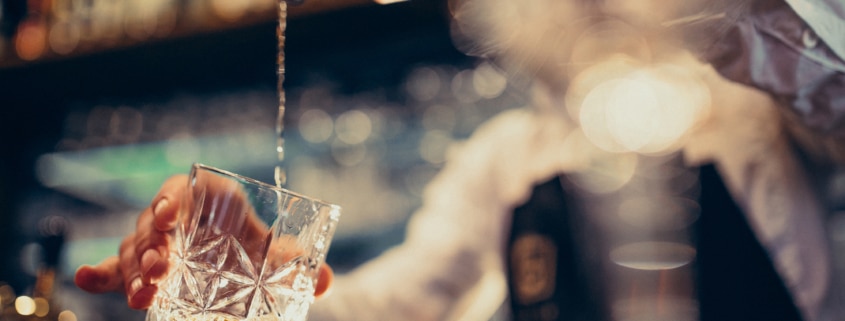 Mann gießt Cocktail in Glas in secret bar wien